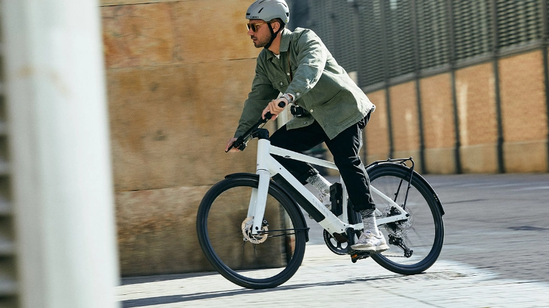 Radfährer fährt mit einem weißen Canyon um eine Straßenecke Radfährer fährt mit einem weißen Canyon um eine Straßenecke